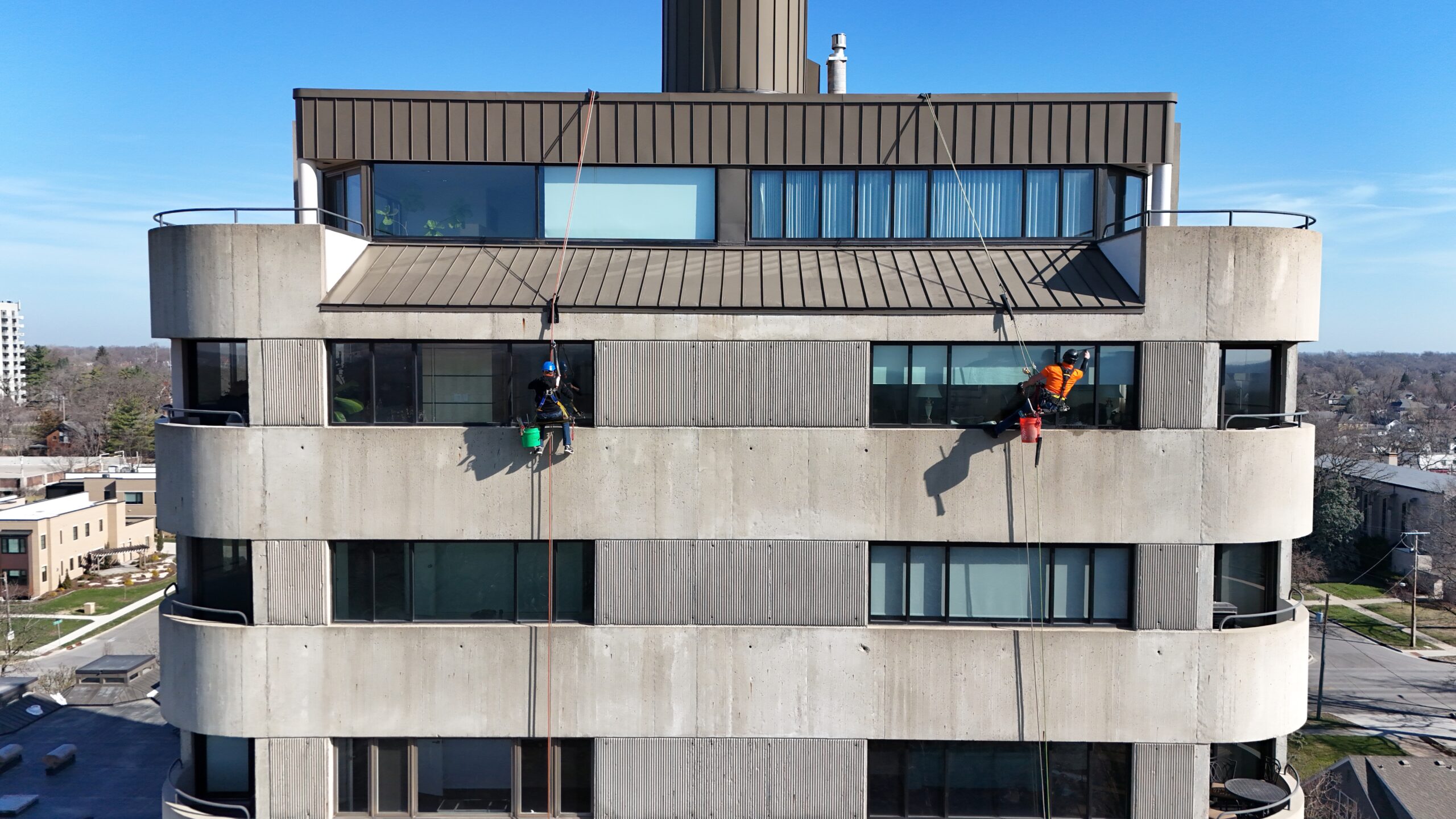 A tall commercial building in Des Moines, IA, where two workers are performing rope-access window cleaning