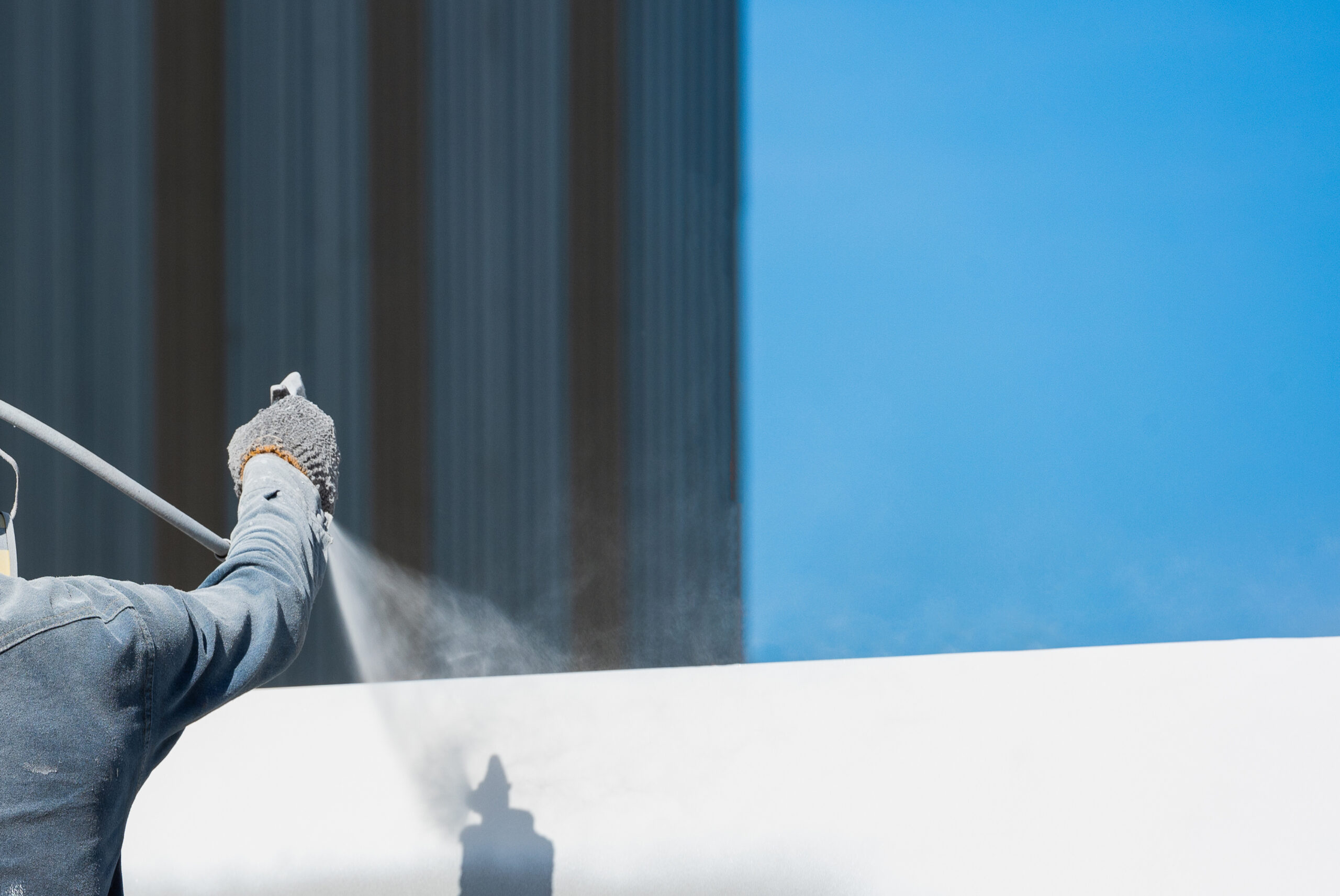 Arm holding spray paint gun painting roof wall on high-rise